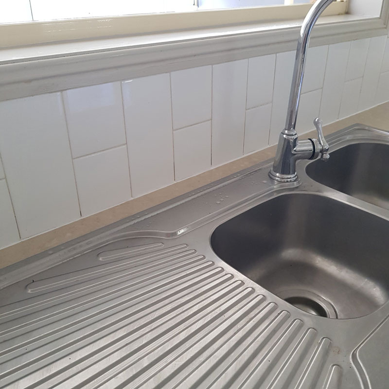 Stainless steel double sink with a faucet in a kitchen.